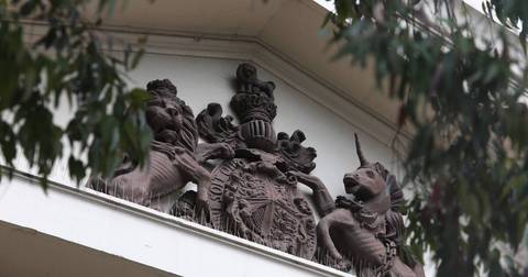 Ornamental stone sculptures featuring mythical figures on building eaves with climbing vines