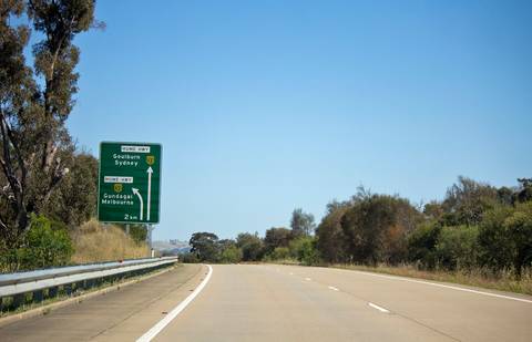 File image: Hume Highway directional sign with trees and guardrail