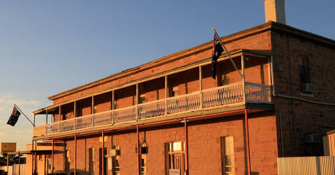 Red brick colonial-era building with wraparound veranda and balcony, traditional Australian pub architecture.