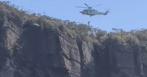 Helicopter hovering above rocky cliff as rescue operation takes place at Illawarra Escarpment
