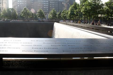 File image: Visitors viewing the 9/11 Memorial's reflecting pool with engraved victim names, NYC skyline and trees visible behind.