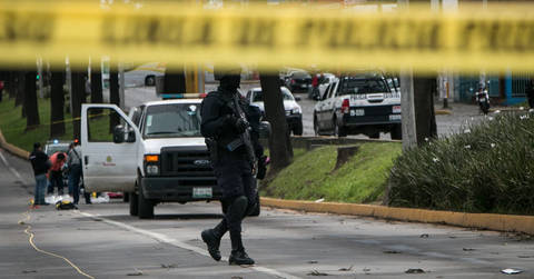 File image: Armed tactical police and officers behind yellow police tape at scene with patrol vehicles.