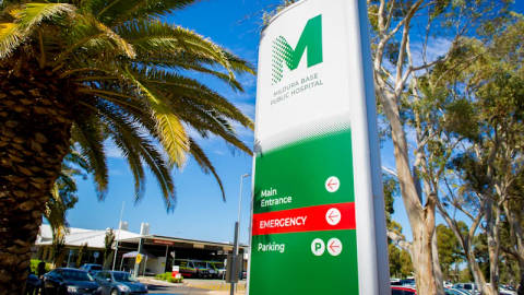 Mildura Base Public Hospital entrance sign with green logo, palm trees, clear sky