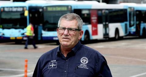 Uniformed transport official standing in front of buses at depot