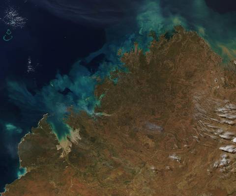 Satellite view of rocky arid landscape meeting vivid turquoise ocean water