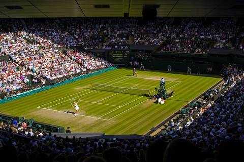 Wimbledon grass tennis court with full stadium seating and spectators