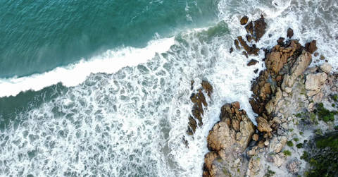 File image: Aerial view of turquoise ocean waves crashing over rocky coastline