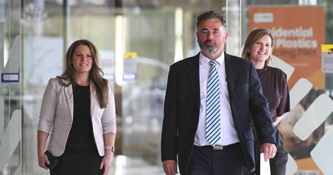 Three people in business attire walking through modern office building interior