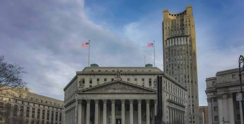File image: Classical courthouse building with columns, U.S. flags, and art deco architecture against blue sky.