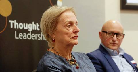 Two people in an indoor professional setting, woman speaking and man listening