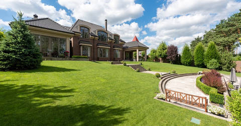 Large brick mansion with extensive manicured lawn and curved driveway