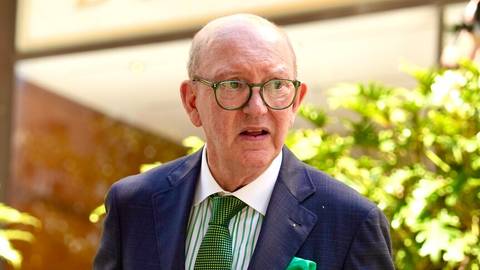 David Allan. Older man in glasses and suit speaking at formal indoor setting