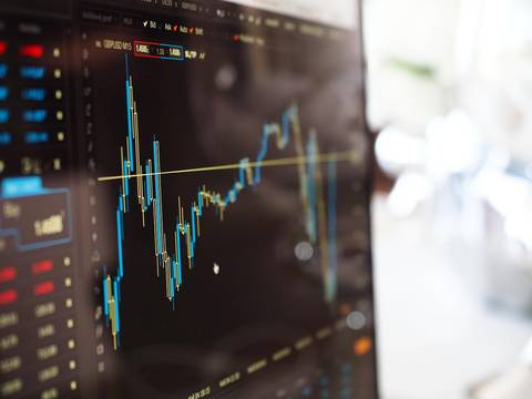 Stock trading candlestick chart on dark terminal display with blue-yellow bars