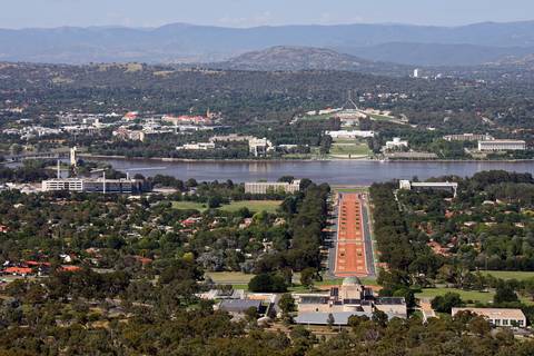 An aerial view of Canberra showing the Australian War Memorial in the foreground, Anzac Parade leading to Lake Burley Griffin, and Parliament House on the hill beyond.