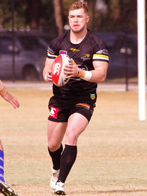 Hudson Young. A rugby league player in a black jersey with yellow trim runs with the ball during a match on a grass field.