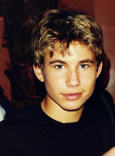 Jonathan Taylor Thomas. A young man with tousled blonde-streaked hair and blue eyes wearing a black t-shirt looks directly at the camera.