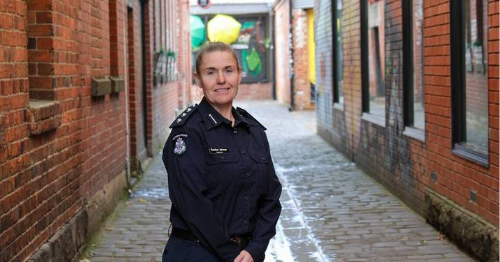 Police officer in dark blue uniform standing in urban brick laneway