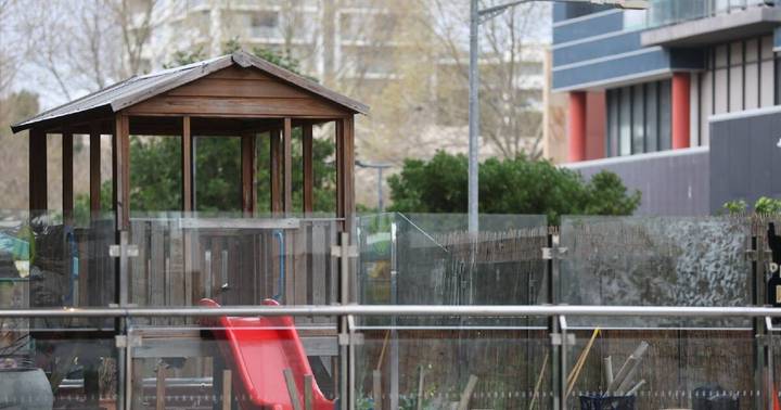 Outdoor playground with wooden structure and red play equipment at childcare facility