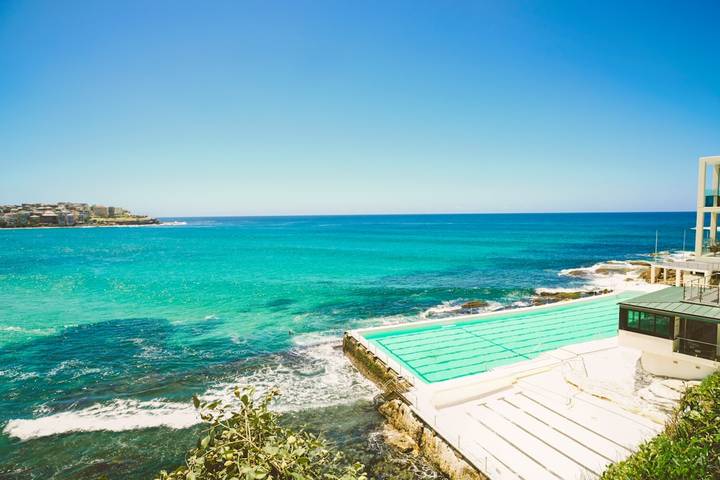 Turquoise infinity pool overlooking pristine ocean, coastal mansion setting