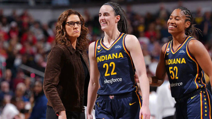 Indiana Fever players numbered 22 and 52 with coach courtside during game against Lynx