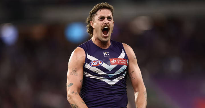 Luke Jackson. AFL player in navy blue Fremantle uniform celebrating during match