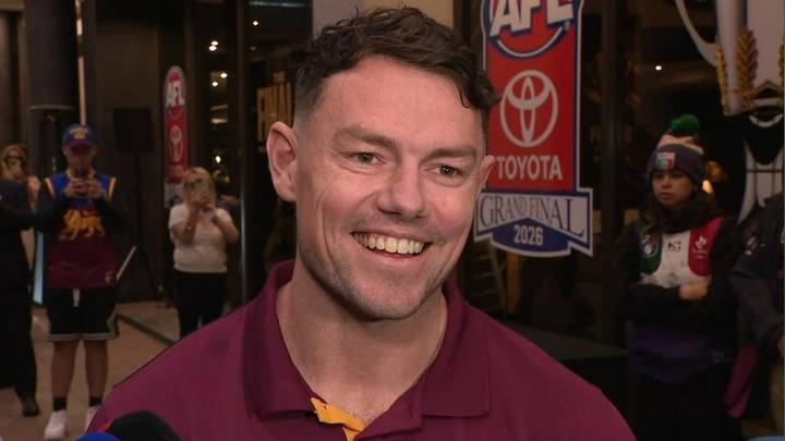Lachie Neale. Man in maroon polo shirt smiling at camera, sports venue with signage behind
