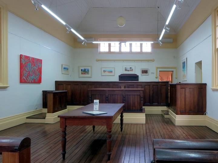 File image: Empty courtroom with wooden bench, judge's chair, and gallery seating.