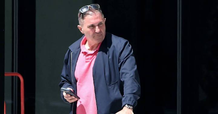 Anthony Di Nardo. Man in dark blazer and pink shirt holding phone on stage