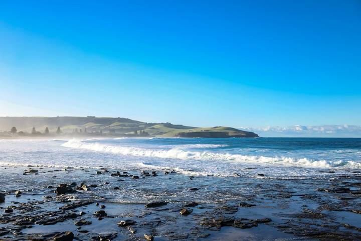 File image: Rocky coastline with breaking waves and green hills beyond