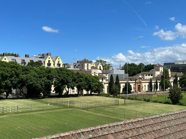 File image: Grass sports courts beside neoclassical heritage building under blue sky