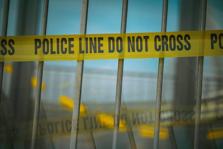 File image: Yellow police line tape on metal fence barrier.