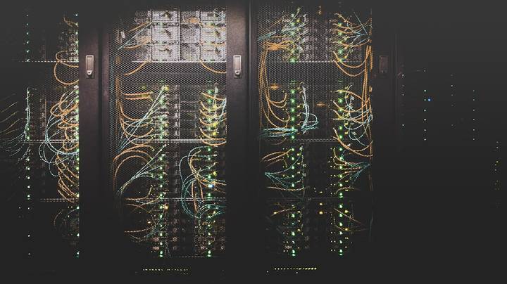 Illuminated server racks and network cables in a data center showing interconnected computing infrastructure.