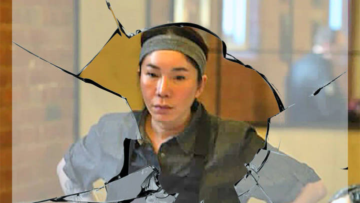 Tinee Suntivatana. Person near shattered glass panel, indoor setting, headband and casual jacket