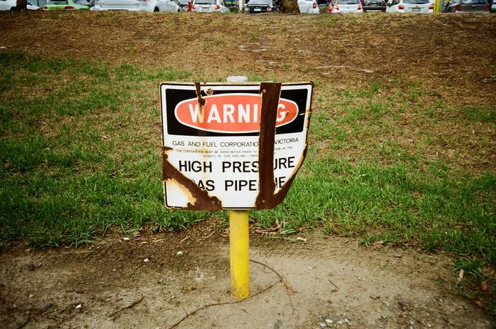 File image: Warning sign marking high-pressure gas pipe on residential lawn with yellow post