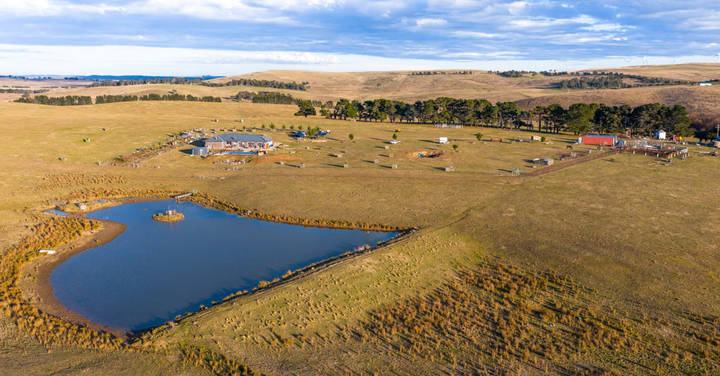Aerial view of rural property with farmhouse, dam, and pastoral fields.