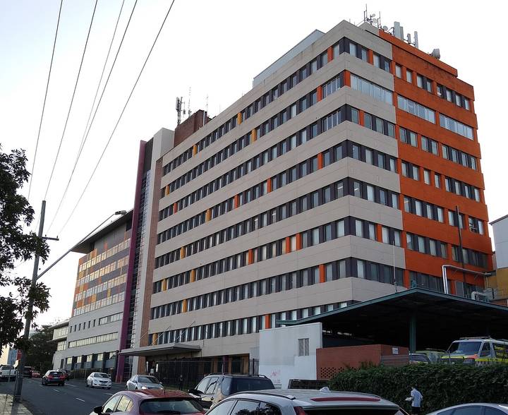 File image: Multi-storey hospital building with orange facade and parked cars