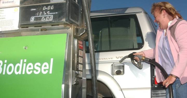 Woman refueling white truck at fuel pump station