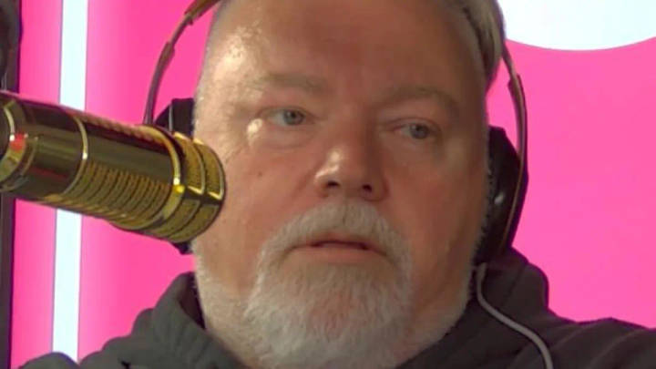 Kyle Sandilands. Bearded man wearing headphones speaking into professional microphone, pink studio background