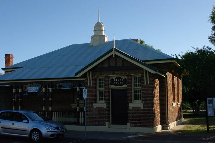 Red brick colonial-style Australian courthouse building with prominent signage and parked vehicle.