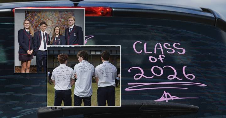 School students in uniforms and white shirts with autographs on grass