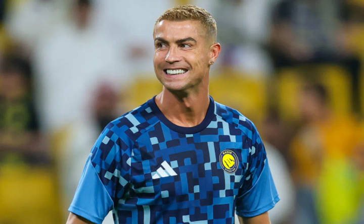 Player in blue Al-Nassr jersey smiling during football match in stadium