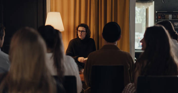 File image: Speaker addressing small group of attentive listeners in interior venue.