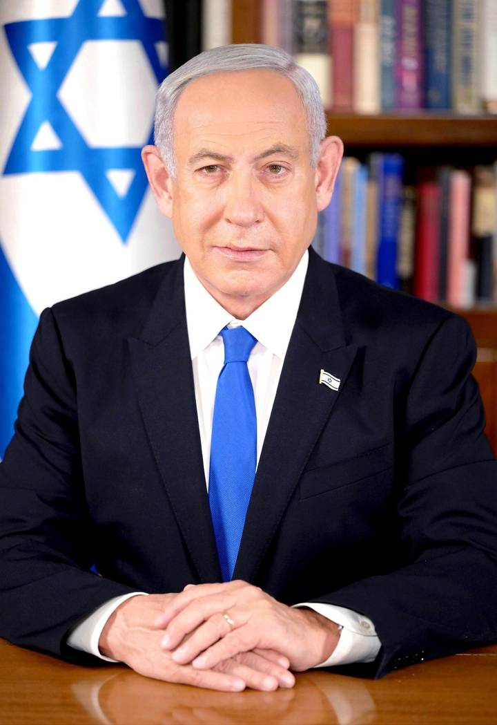 File image: Man in dark suit and blue tie at official desk with Israeli flag background.