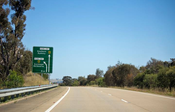 File image: Hume Highway directional sign with trees and guardrail