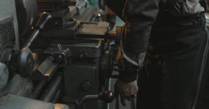 File image: Worker's hand at industrial machine in workshop, demonstrating machinery operation hazard.