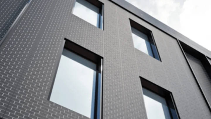 Modern building facade with dark-framed rectangular windows and gray textured exterior
