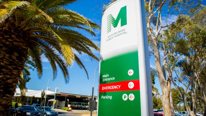 Mildura Base Public Hospital entrance sign with green logo, palm trees, clear sky