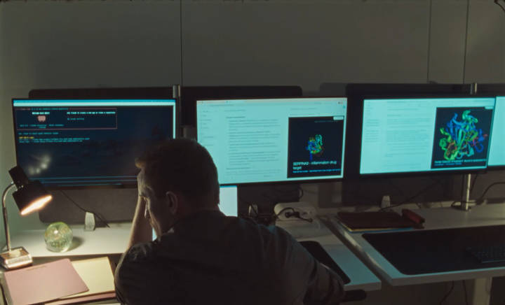 Developer working at multi-monitor workstation displaying code and development tools.