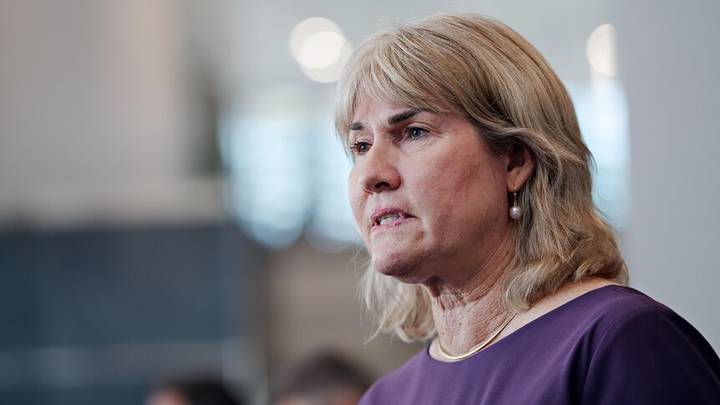 Eva Lawler. Profile of person in purple shirt against blurred office background