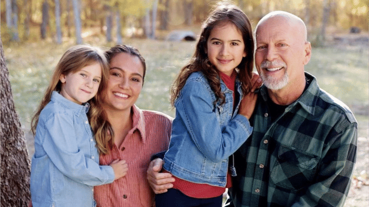 Family of four posing outdoors smiling at camera in casual clothing